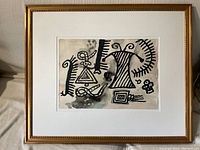 Full front view of framed painting showing gold frame, white mat and abstract artwork