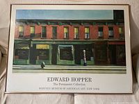 Full view of the framed poster showing Edward Hopper's painting 'Early Sunday Morning' with the title and museum name below.