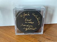 Front view of the signed black hockey puck with gold inscription
