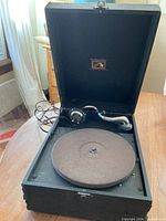 Top view of portable suitcase gramophone with turntable and tonearm visible, black textured case interior.