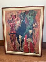 Front view of framed abstract print showing five stylized human figures in warm colors inside teak frame with cream matting.