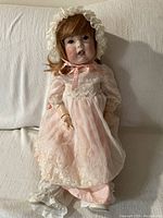 Full view of the SFBJ Paris bisque doll in lace pink dress and bonnet