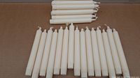 Photo showing 26 cream colored taper candles laid out on a surface, highlighting size and color.