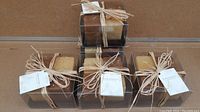 Five packs of Pure Moment candles, each pack containing 4 candles tied with raffia and packaged in clear plastic boxes.