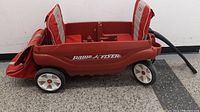 Side view of the red Radio Flyer two-seater wagon with padded seats and pull handle