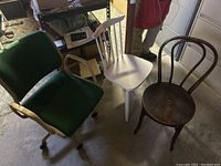 Three chairs in a room: green office chair with caster wheels, white wooden spindle back chair, dark wood bentwood chair