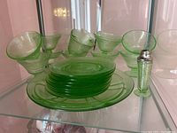 Eight footed sherbet cups arranged behind stacked plates with salt shaker at right.