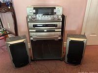 Photo of full Emerson stereo system with cabinet and two surround sound speakers positioned on each side, showing overall setup and condition.