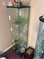 Full view of tall glass display case with items inside for display only, showing clear glass with metal frame and door handles on the front.