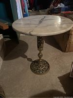 Full view of fully assembled marble side table with round marble top and ornate metal base.