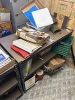 Black metal shelving unit with particle board shelves, top and middle shelves visible with some objects placed. Shelving unit measured approximately 49x24x36 inches.