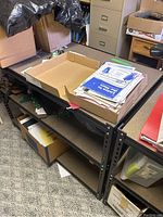 Metal shelving unit with various papers, boxes, and miscellaneous items on it to show size and shelves