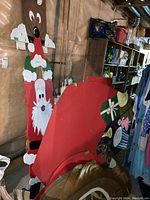 Photo of large wooden red sleigh with Santa figure standing behind it, showing details of the painted wood and structure.