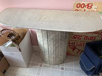 Granite pedestal side table with curved granite top and fluted granite base, light veining visible.