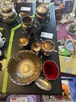 Top-down view of silver plated tea set including teapot, sugar bowl, creamer, footed bowl, small tray, and velvet lined box on black table surface