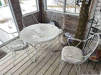 Wide shot of the round patio table and four chairs on porch, showing overall condition and set contents