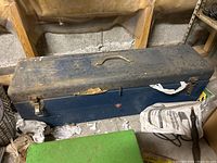 Closed vintage blue metal tool box with a handle and two latch closures, showing wear and dirt on the surface, with Canadian Tire red triangle logo visible on the front.