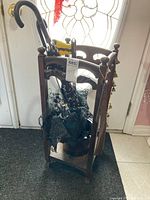 Overall view of vintage wooden umbrella stand holding umbrella and parasol by a door.