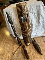 Photo showing all four African wooden carvings, including the tall mask with geometric detail and three smaller figurines arranged on countertop.