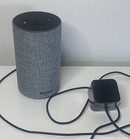 Front view of Amazon Echo smart speaker and power adapter on white surface