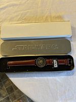 Pre-owned Star Wars limited edition watch in metal branded case and outer cardboard box on fabric surface.