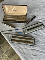 Overview of all pens in cases and loose with refills visible on a white cloth surface