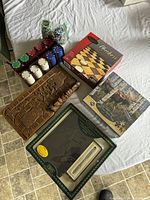Overall layout of lot items on table including crib board with poker chips, boxed Checkers game, unopened Hayden Lambson puzzle, and boxed Cross pen set.
