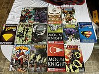 Photo showing all 14 comics laid out on a flat surface with various titles visible