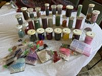 Full view of various plastic vials and small bags of seed beads on table.