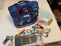 Overall view of scrapbooking supplies including Fiskars branded scissor organizer, scissors, paper punches, and a paper trimmer on a white surface
