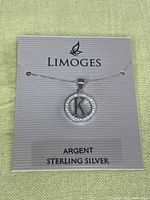 Sterling silver necklace with initial 'K' pendant displayed on Limoges branded card indicating sterling silver material and Argent mark.
