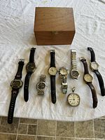All 9 watches laid out in front of wood box