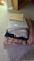 Stack of folded king size quilted blanket and throws on carpet