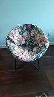 Front-facing view of the floral cushioned tub chair showing its round shape and colorful cover.