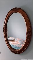 Full view of the oval mirror showing the entire gold frame and reflective surface.