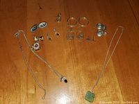 Full view of all jewelry items including necklaces, earrings, and cufflinks laid out on wooden surface.