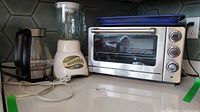 Kitchen counter showing the Cuisinart convection toaster oven broiler, Oster blender, and electric kettle.