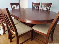 Full view of oval table with leaf inserted and six matching chairs from front-left angle