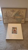 Photo showing both framed art pieces on carpet: vintage Ottawa map and sailboat print.