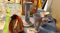 Overview of the lot showing olive dish, Wedgwood candle holder and cup, Royal Copenhagen pitcher, and small plate.