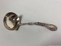 Full side view of the sterling silver ladle showing ornate handle and monogram.