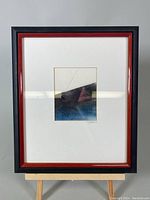 Framed abstract geometric mixed media painting with mostly black, red, and blue tones and embossed geometrical shapes.