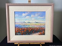 Full view of framed colorful floral field painting with blue sky and clouds, signed SUNNY 5.91 at bottom left corner.
