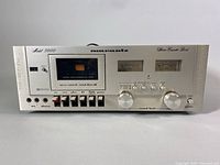 Front view showing cassette compartment, transport controls, dual VU meters and level knobs