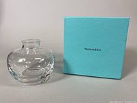 Front view of clear Tiffany & Co. crystal bud vase next to original light blue Tiffany box.
