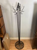 Full height view of the wrought iron coat rack showing multiple hooks and slender panel design.