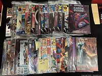 50 comic books arranged in rows on a table with visible front covers protected in plastic bags