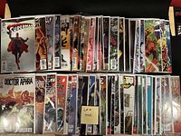 Photo showing 50 comics bagged and boarded, displayed in two rows, featuring diverse titles and colorful covers.