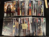 Photo of two rows of comic books, all in plastic bags with backing boards, showing covers from a wide selection of comics including The New Avengers and Batman Confidential.