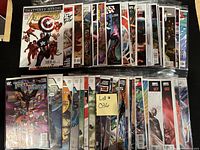 Photo showing a collection of approximately 50 high grade comics, each bagged and boarded, featuring covers with characters such as Captain America and members of Teen Titans and Justice League.